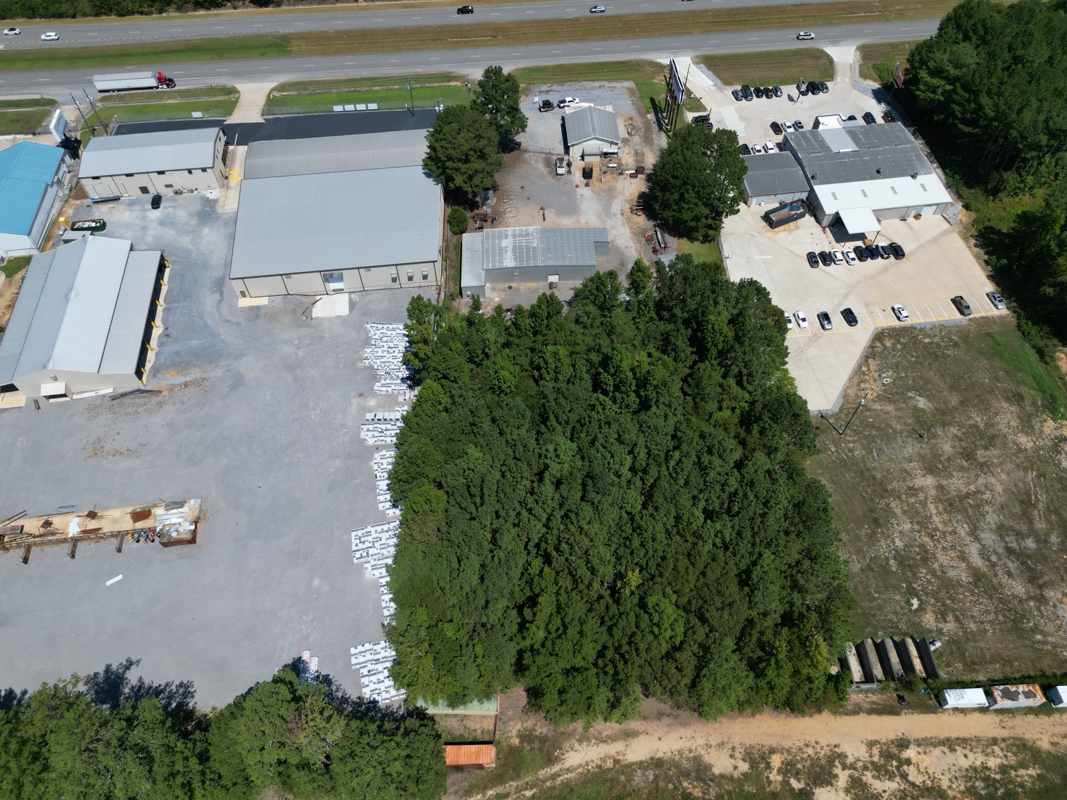 High aerial showing the existing improvements and wooded rear acreage.